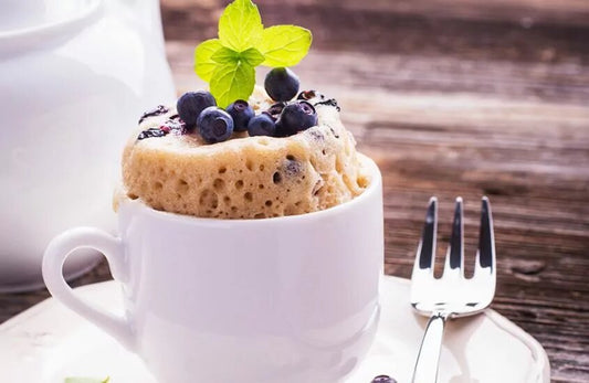 Photo of a mug cake with blueberries at the top 