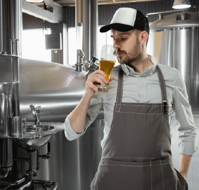 Brewer holding glass of beer while smelling the beer