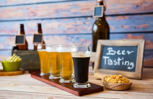 Four beer glasses on a tray with a sign on the back stating "beer tasting"