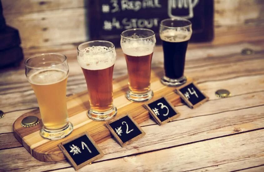 four glasses of beer are on a table next to each other labeled from one to four. 