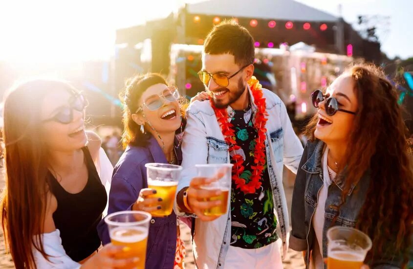 Group of friends at a festival smiling while holding beer cups