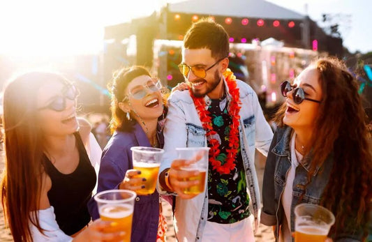 Group of friends at a festival smiling while holding beer cups