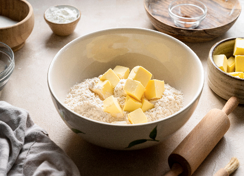 A bowl of flour with pieces of cubed butter inside