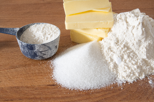 Baking ingredients such as flour, sugar, and butter are placed next to each other